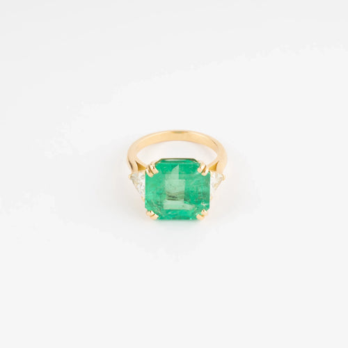 Yellow gold ring adorned with an emerald-cut emerald flanked by triangle diamonds