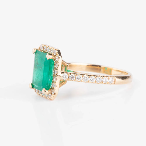 Yellow gold ring adorned with an emerald surrounded by diamonds